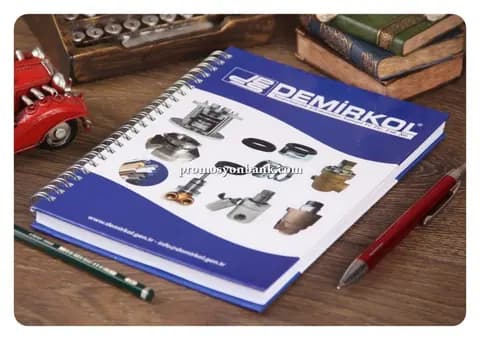 promosyon mavi beyaz baskılı kapaklı metal spiralli katalog defter, ahşap masa üzerinde çapraz çekim