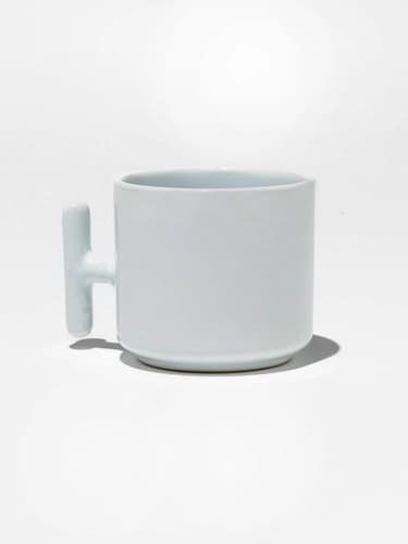 Beyaz promosyon latte fincanı; dikey kulplu yan çekim, gölgeli zemin