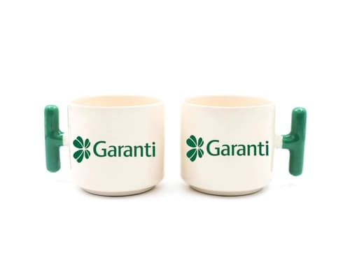 İki adet koyu yeşil kulplu krem promosyon latte fincanı, banka logosu baskılı