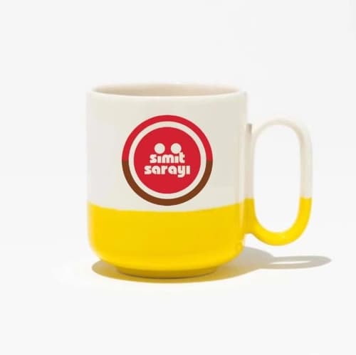 Sarı tabanlı beyaz porselen promosyon kupası; ön yüzde kırmızı daireli logo baskısı