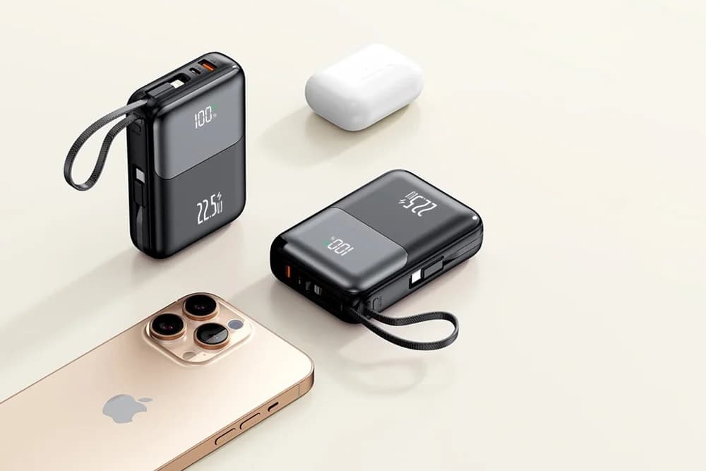 Bej zeminde iki siyah powerbank, beyaz kulaklık kutusu ve akıllı telefon.