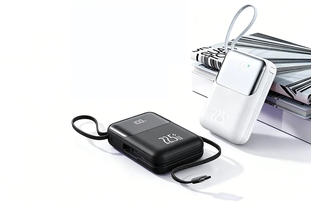 Siyah ve beyaz powerbank dergilerin yanında; ekranlı ve kablolu.