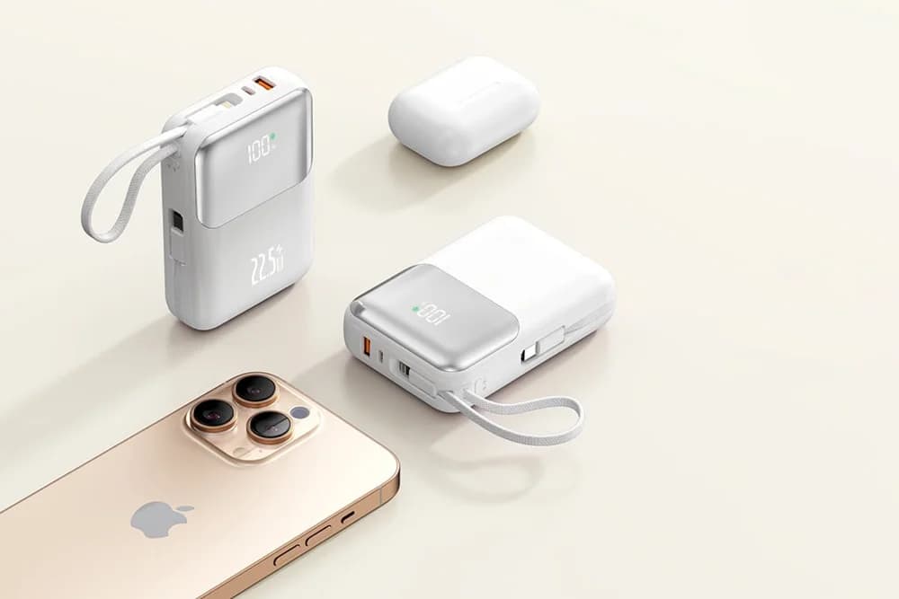 Telefon, kulaklık kutusu ve iki beyaz powerbank açık masada.
