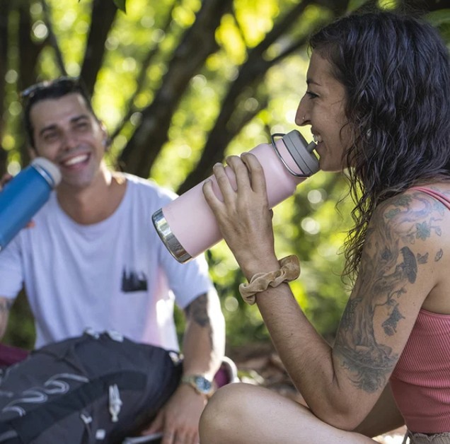 Açık havada promosyon Klean Kanteen termoslarından içecek içen iki kişi.