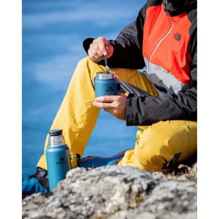 Şişe ve termosla açık hava yürüyüşü yapan kişi, doğa ortamında içecek hazırlıyor.