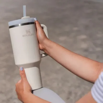 Yol kenarında açık havada, kişisel kullanım için tasarlanmış beyaz Stanley termosu, pipetli ve taşınabilir, pratik ve şık tasarıma sahip, promo ürünleri ile reklam ve markalaşma amacıyla tercih edilen bir ürün.